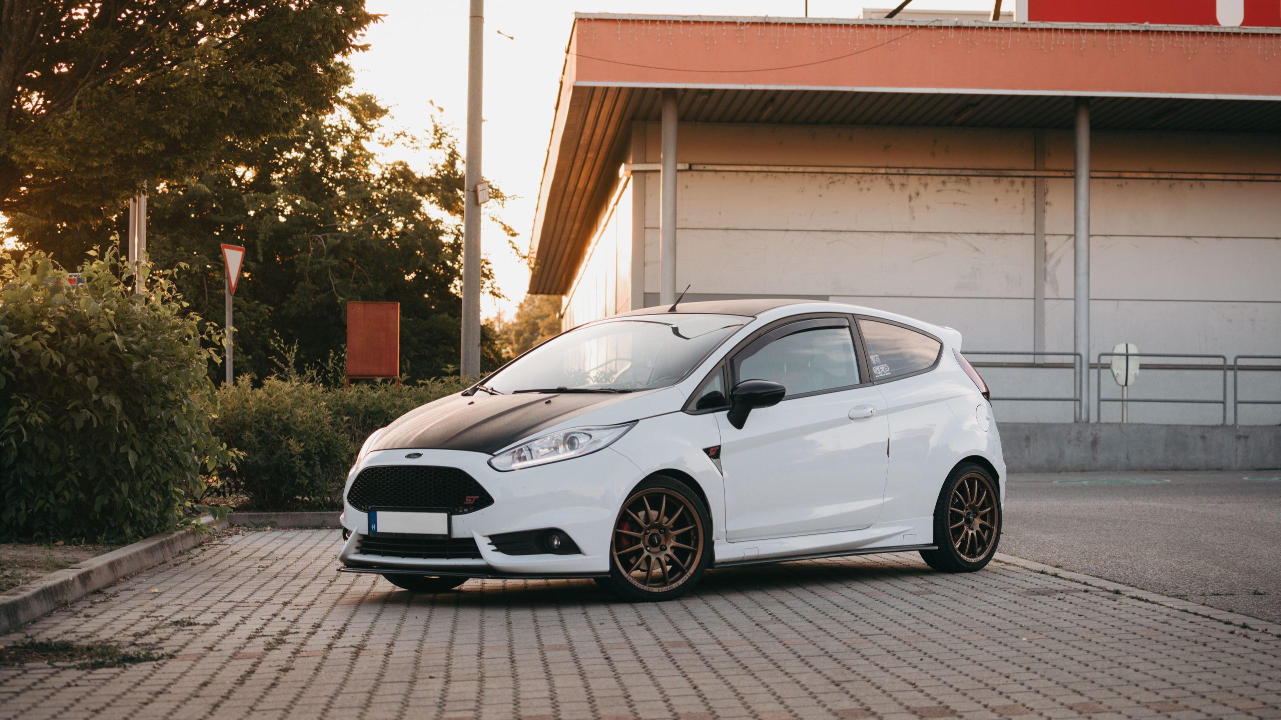 Clio blanche garée près immeuble au coucher soleil