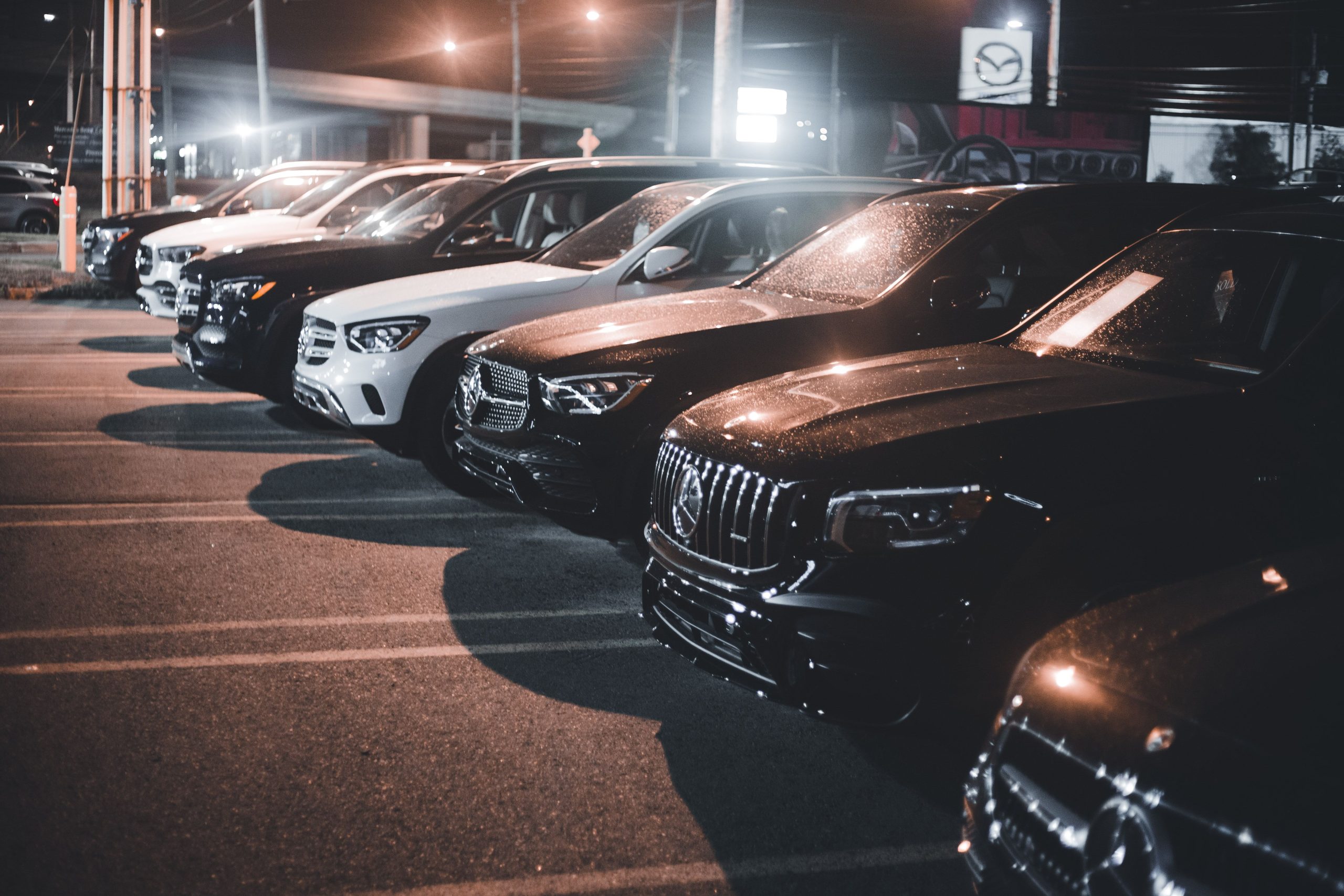 Rangée de voitures de luxe au parking, éclairées la nuit