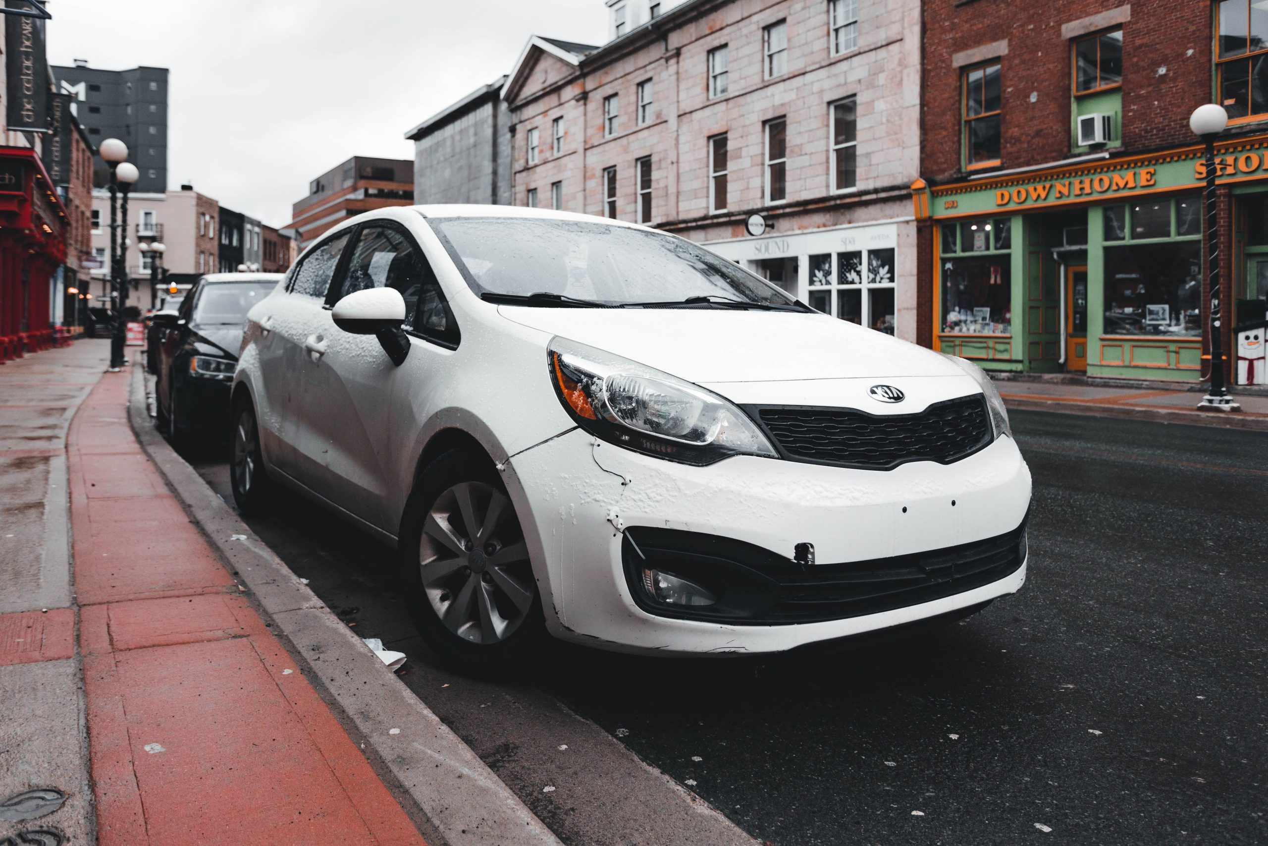 Voiture blanche stationnée sur rue mouillée après pluie