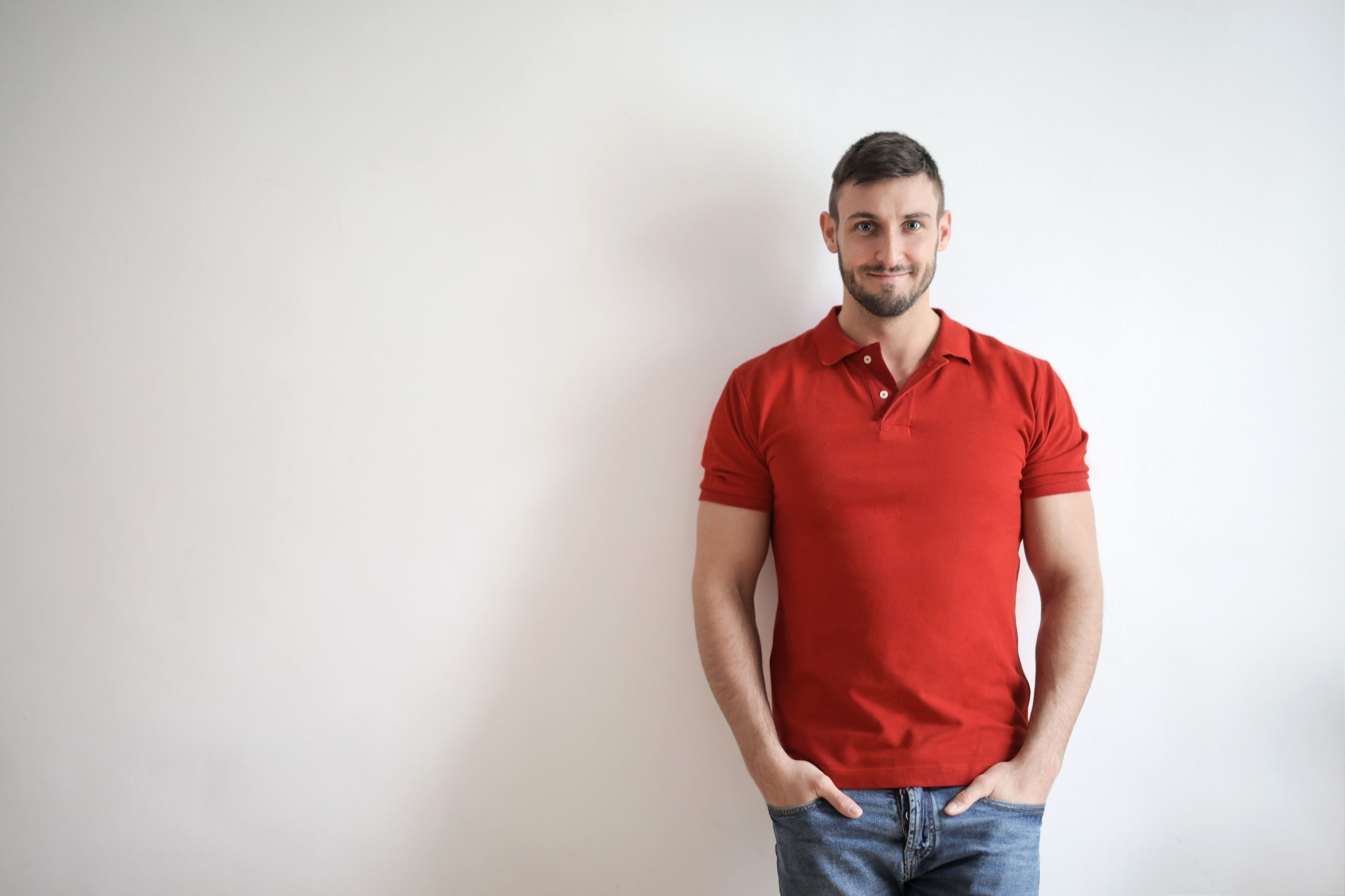Homme en polo rouge devant mur blanc